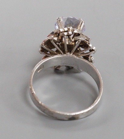A modern white metal (tests as 18ct) and solitaire white sapphire set flower head ring, in a raised setting, size S/T, gross weight 8.1 grams.